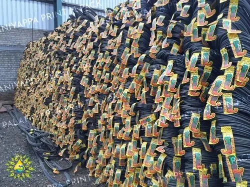 A long row of tagged steel bar bundles stacked in a yard beside a shed