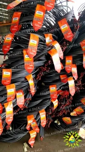 A tall stack of steel bar coils in a warehouse with a bright orange-red tag on each