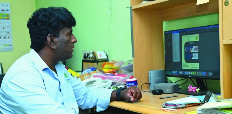 A man at a design desk looking at a tag design on a computer screen.